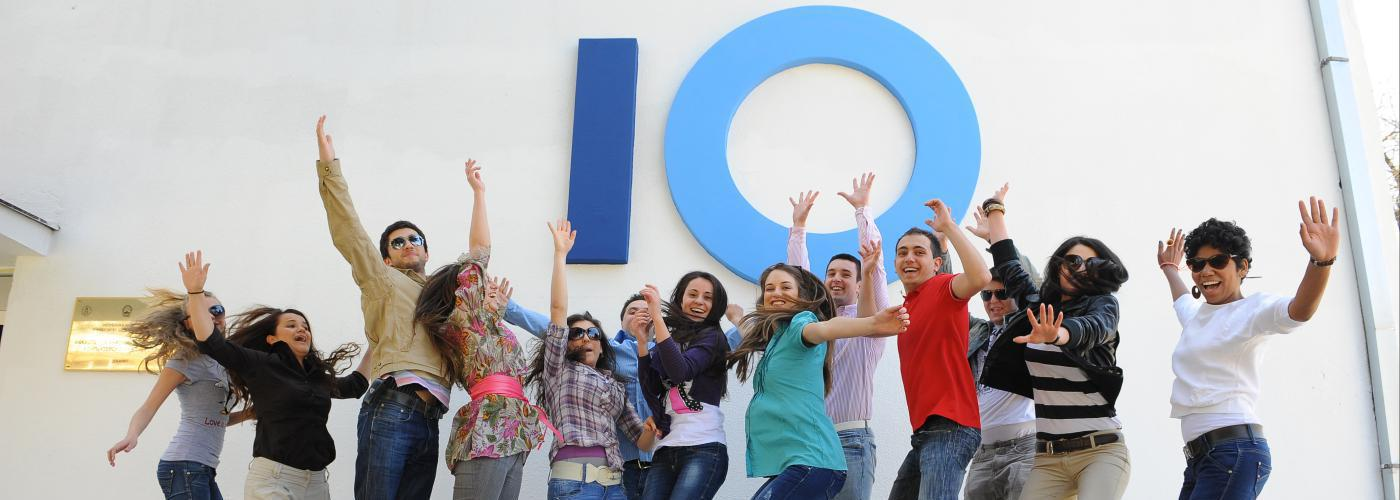 Young people jumping and raising their hands. Logo of the Faculty of Computer Science in the background.